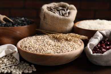 Photo of Different types of cereals, seeds and legumes on wooden table