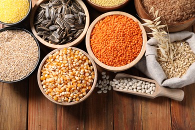 Different types of legumes, seeds and cereals on wooden table, flat lay