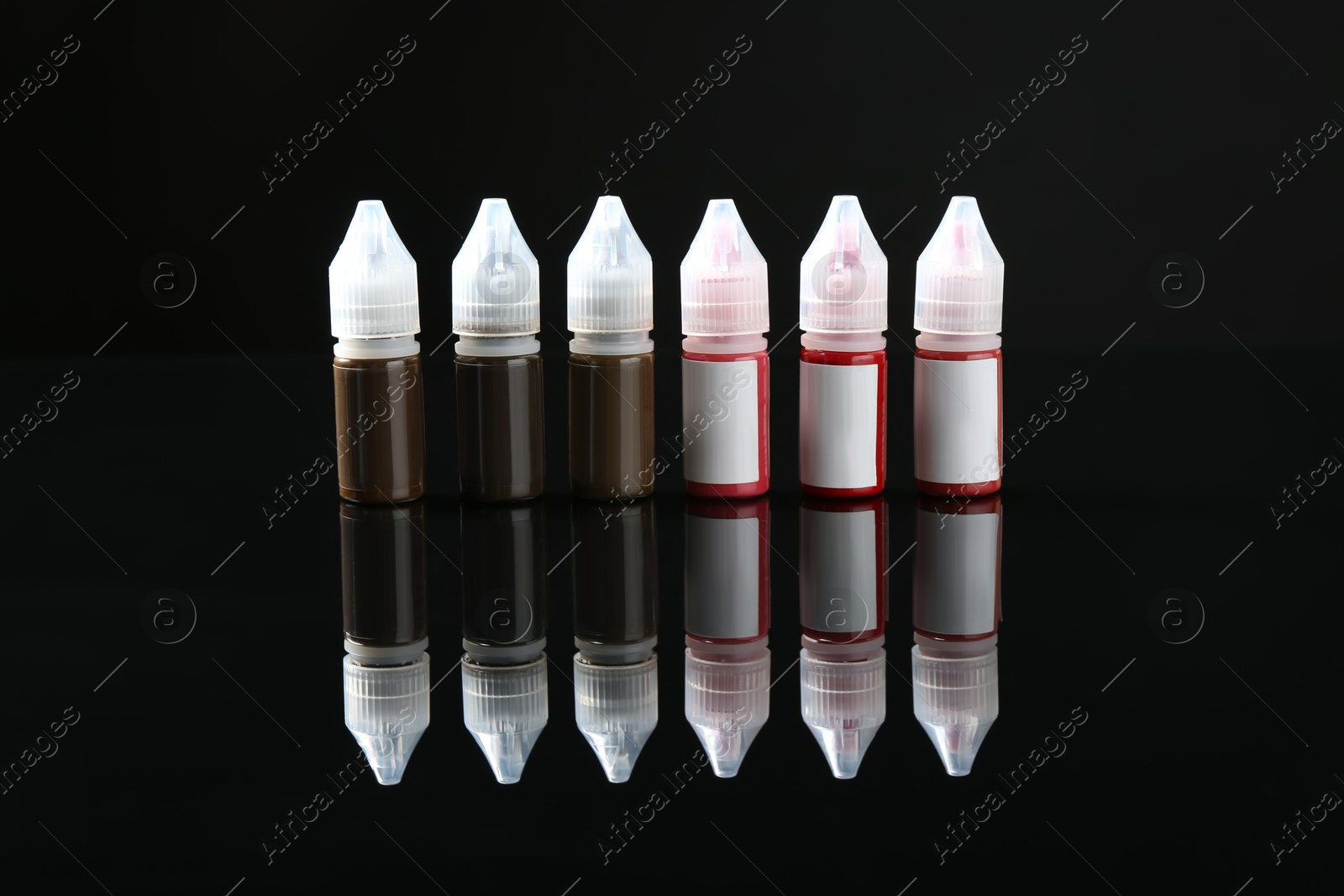 Photo of Bottles of pigments for permanent makeup on black mirror surface