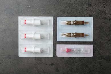 Many disposable cartridge systems for permanent makeup on grey background, top view