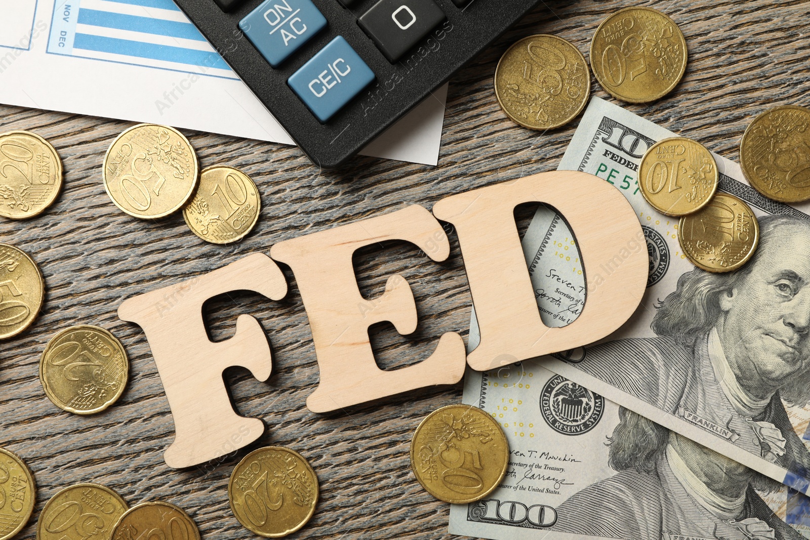 Photo of Letters Fed (Federal Reserve System), coins, dollar banknotes and calculator on wooden table, flat lay