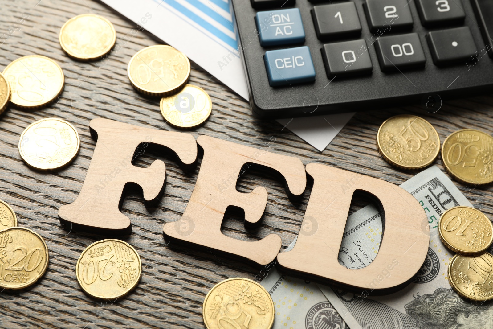 Photo of Letters Fed (Federal Reserve System), coins, dollar banknotes and calculator on wooden table