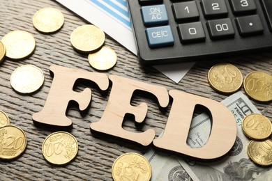 Photo of Letters Fed (Federal Reserve System), coins, dollar banknotes and calculator on wooden table