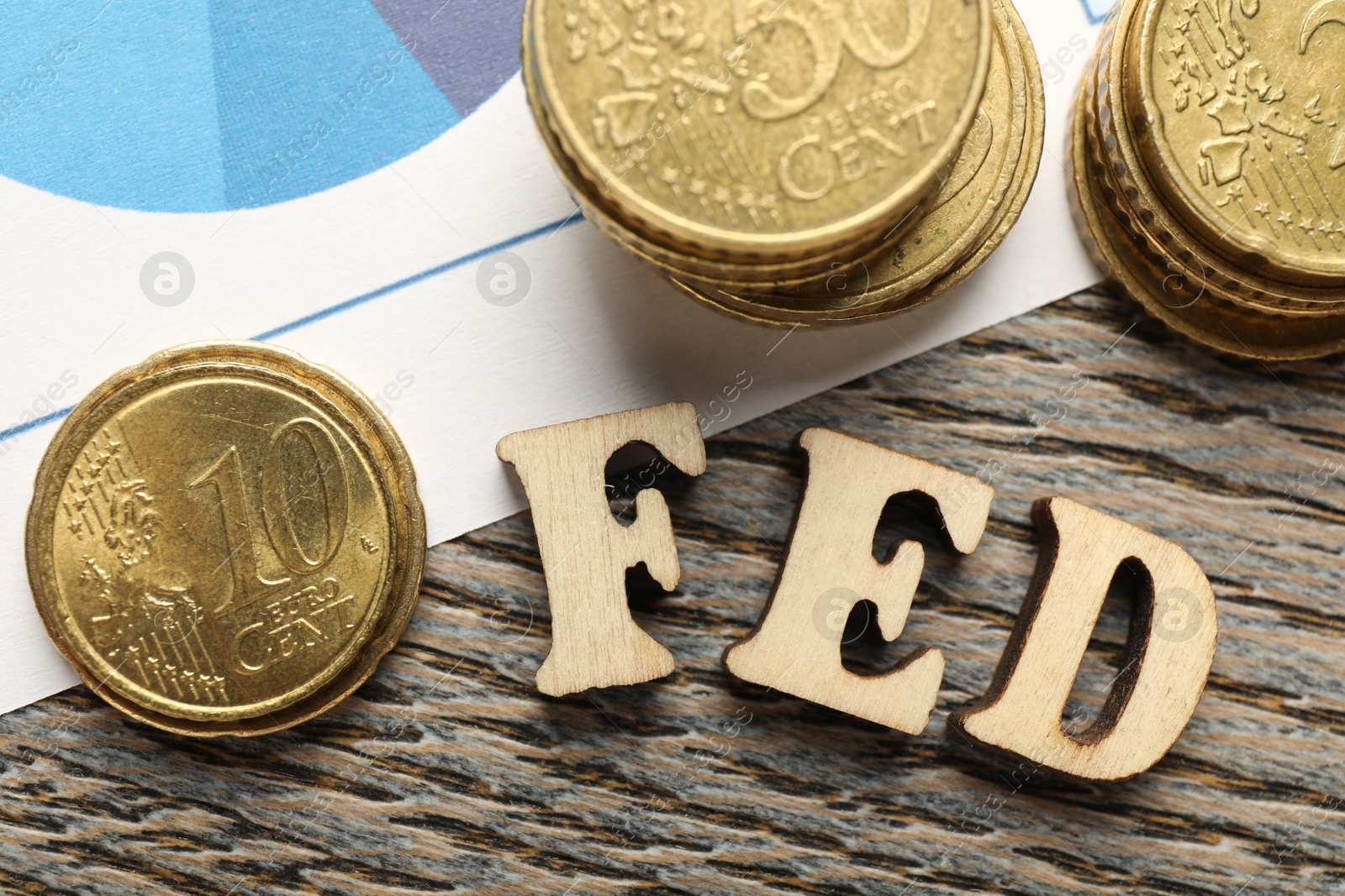 Photo of Letters Fed (Federal Reserve System) and coins on wooden table, flat lay