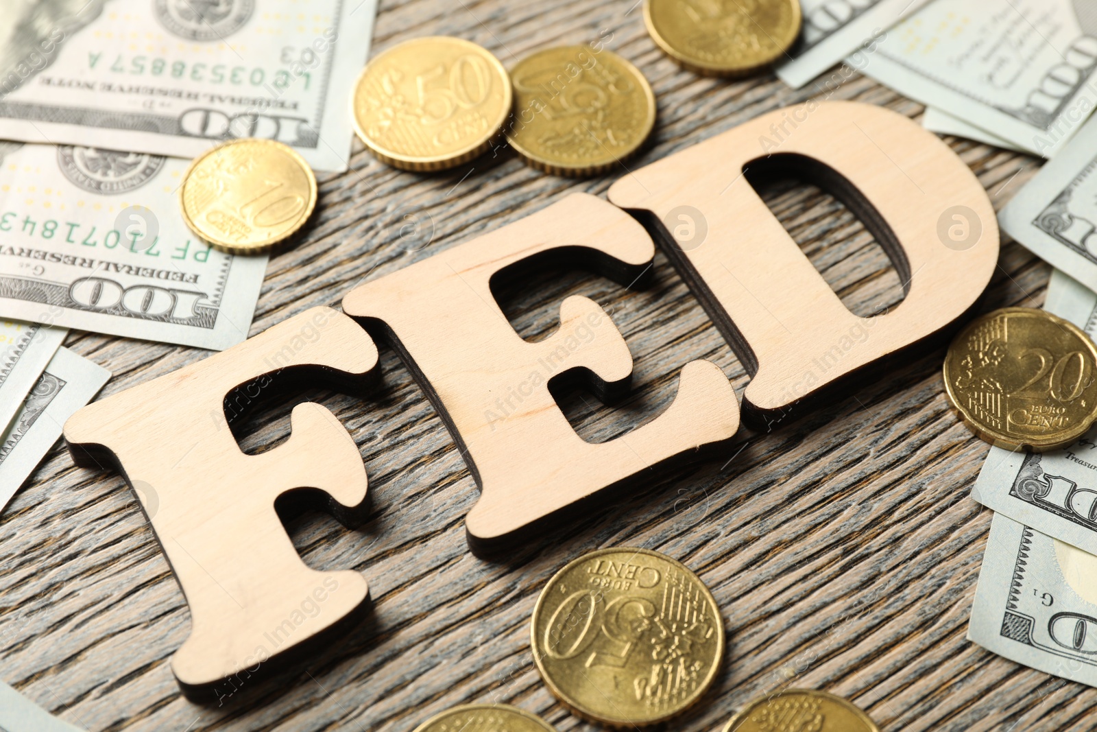 Photo of Letters Fed (Federal Reserve System), dollar banknotes and coins on wooden table, closeup