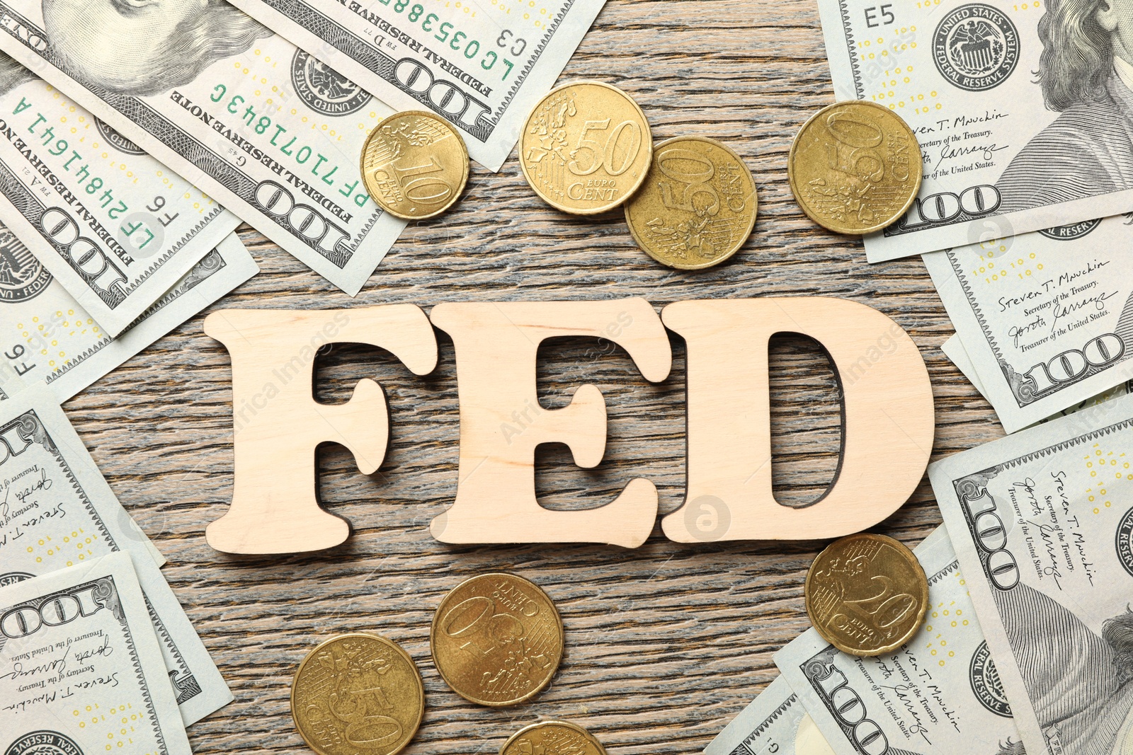 Photo of Letters Fed (Federal Reserve System), dollar banknotes and coins on wooden table, flat lay