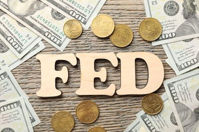 Photo of Letters Fed (Federal Reserve System), dollar banknotes and coins on wooden table, flat lay