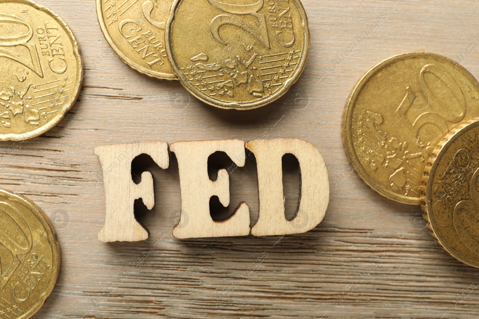 Photo of Letters Fed (Federal Reserve System) and coins on wooden table, flat lay