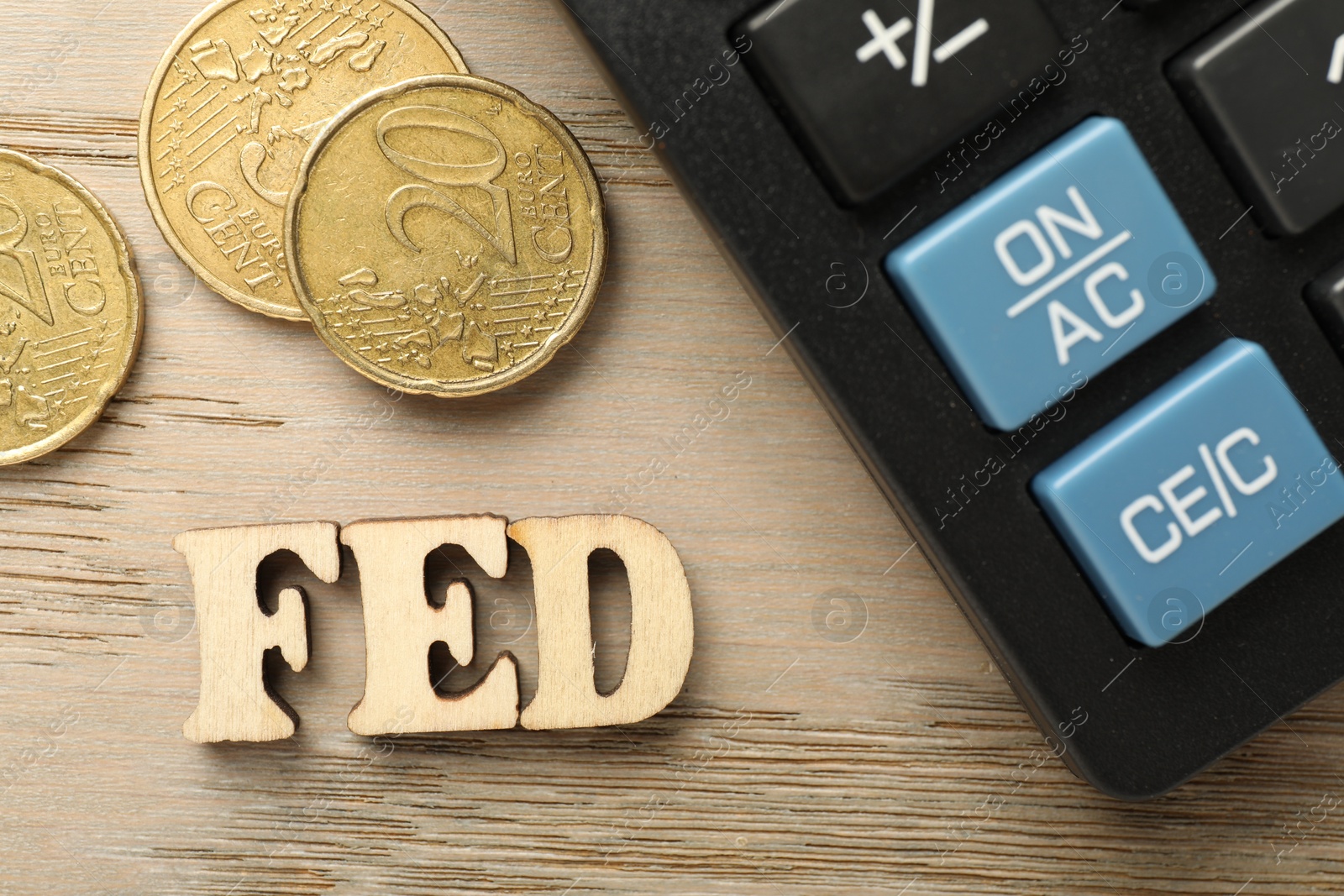 Photo of Letters Fed (Federal Reserve System), calculator and coins on wooden table, flat lay