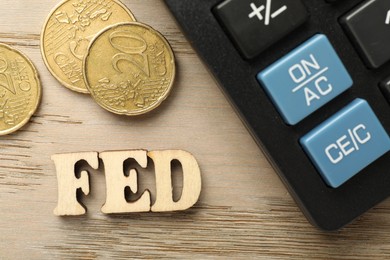 Photo of Letters Fed (Federal Reserve System), calculator and coins on wooden table, flat lay