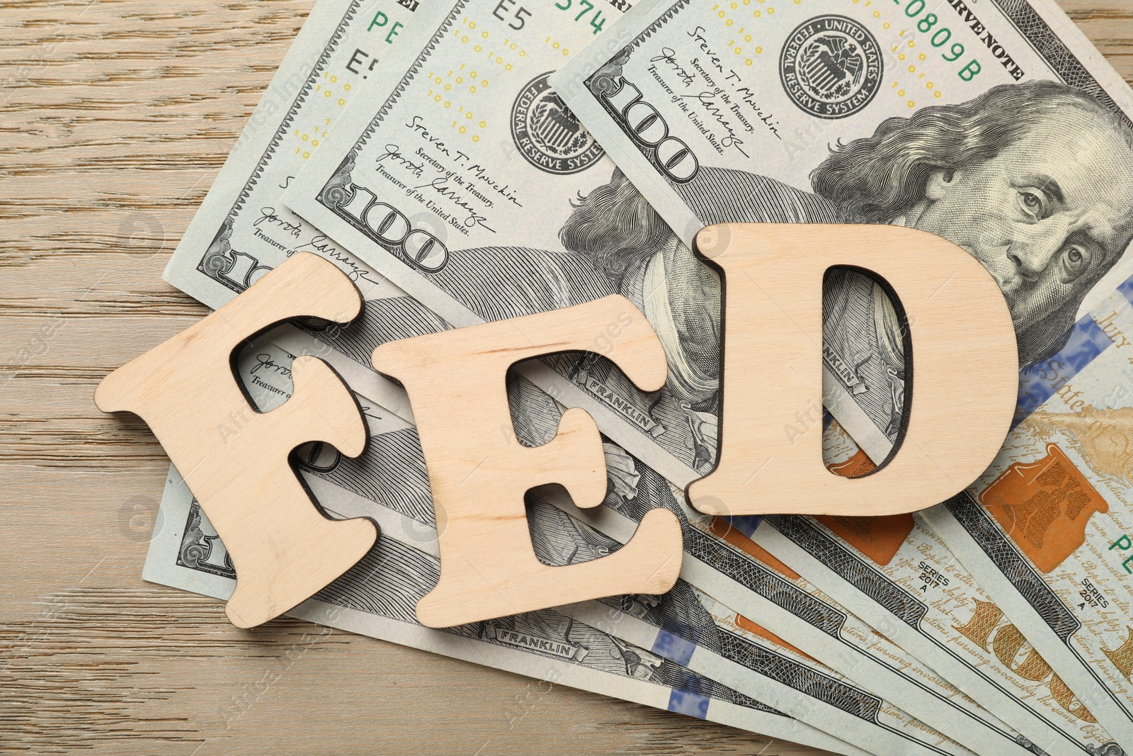 Photo of Letters Fed (Federal Reserve System) and dollar banknotes on wooden table, flat lay