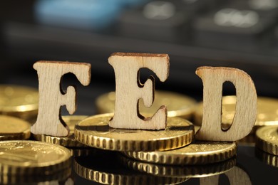 Photo of Letters Fed (Federal Reserve System) and coins on mirror table, closeup