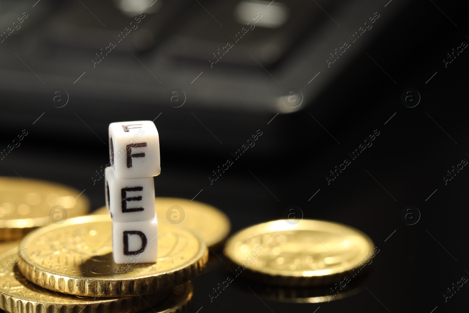 Photo of Cubes with letters Fed (Federal Reserve System) and coins on black table, closeup. Space for text