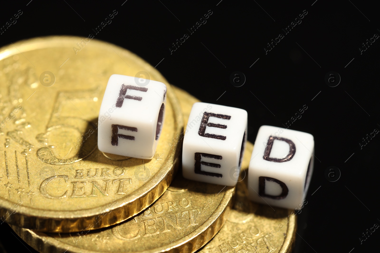 Photo of Cubes with letters Fed (Federal Reserve System) and coins on black table, closeup