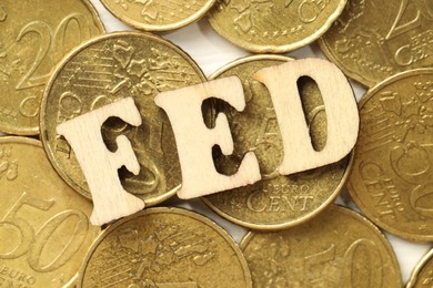 Photo of Wooden letters Fed (Federal Reserve System) and coins on white table, flat lay