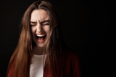 Portrait of scared woman on black background. Space for text