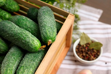 Photo of Fresh green cucumbers in wooden crate on table, closeup