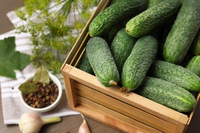 Photo of Fresh green cucumbers in wooden crate on table, closeup