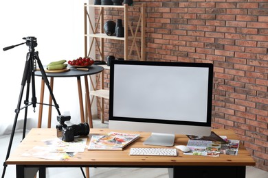 Photo of Computer, camera, magazines and vegetables on table in studio. Food photography