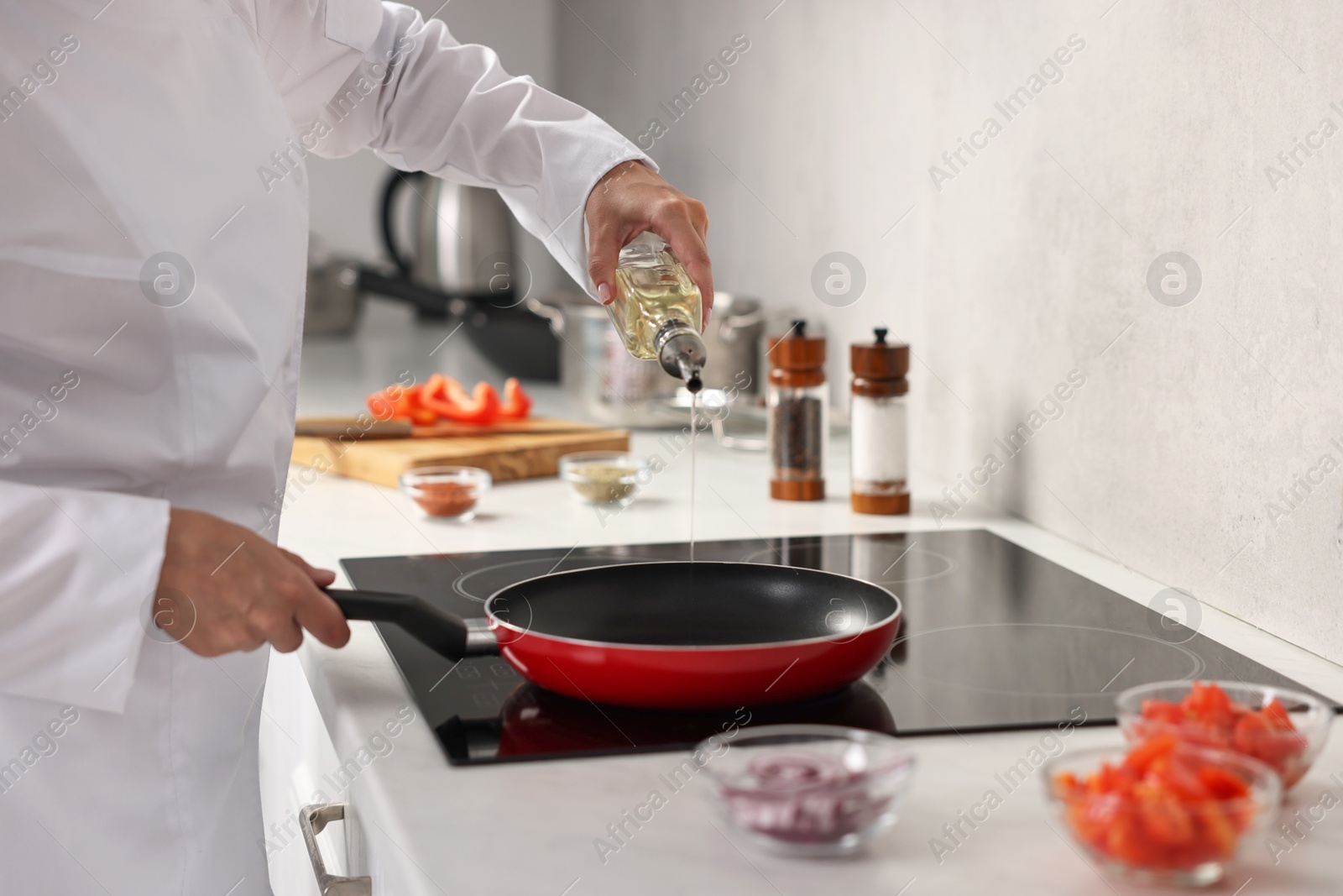 Photo of Professional chef pouring oil into frying pan in kitchen, closeup