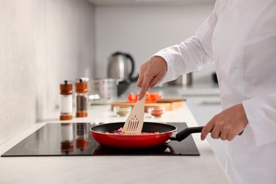 Photo of Professional chef cooking delicious food on stove in kitchen, closeup