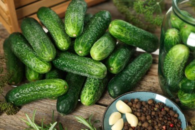 Photo of Pile of fresh cucumbers and spices on wooden table, closeup. Preparation for pickling