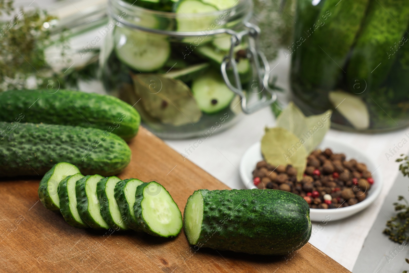 Photo of Board with fresh cut cucumber and spices on light table, closeup. Preparation for pickling