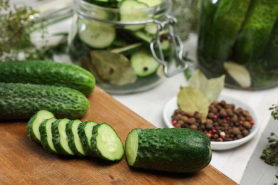 Photo of Board with fresh cut cucumber and spices on light table, closeup. Preparation for pickling