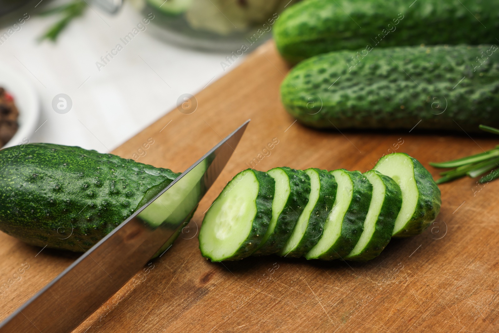 Photo of Cutting fresh ripe cucumber at table, closeup