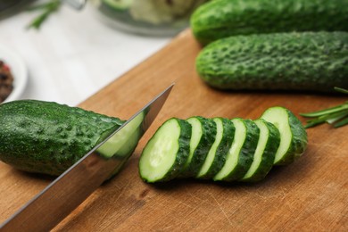 Cutting fresh ripe cucumber at table, closeup