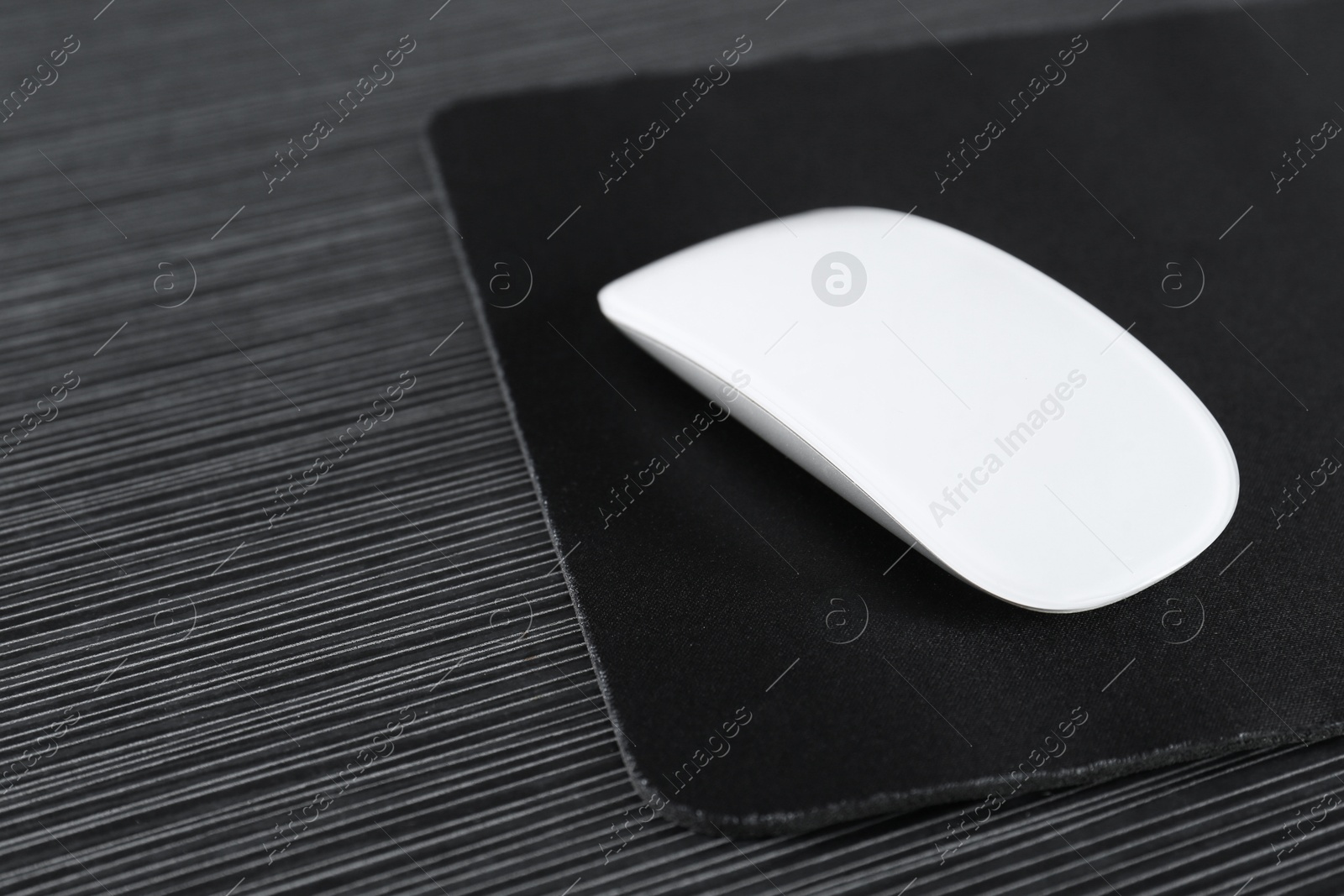 Photo of White computer mouse with mousepad on black wooden table