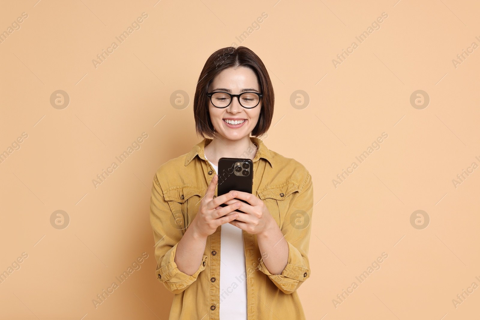 Photo of Smiling woman with smartphone on beige background