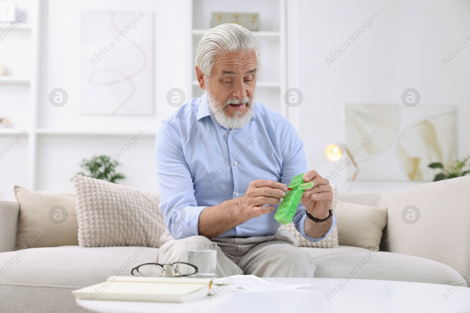 Photo of Senior man with pill and organizer at home