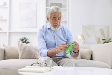 Senior man with pill and organizer at home