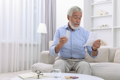 Senior man with pills reading medicine instruction at home