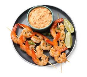 Photo of Skewers with delicious grilled shrimps, lime and sauce isolated on white, top view