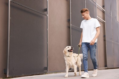 Happy owner walking with cute Golden Retriever dog outdoors, low angle view. Space for text