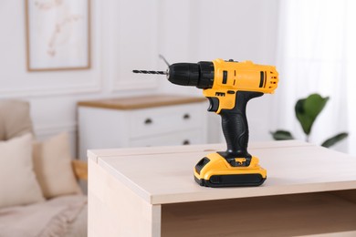 Photo of Cordless electric screwdriver on wooden table at home. Space for text