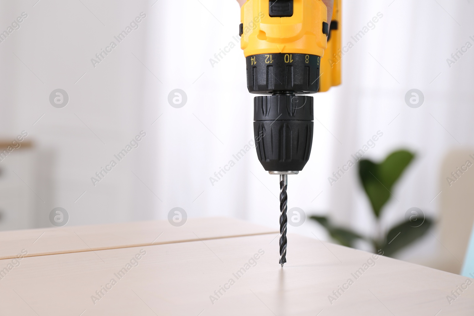 Photo of Woman with electric screwdriver assembling furniture at home, closeup. Space for text