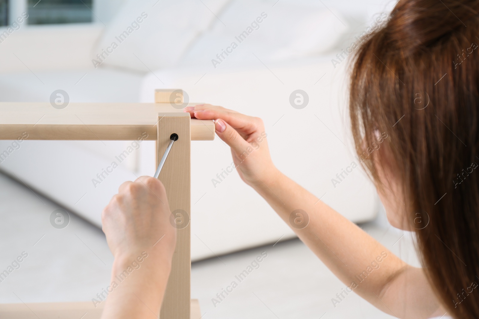 Photo of Woman with screwdriver assembling furniture at home, closeup