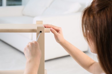 Woman with screwdriver assembling furniture at home, closeup