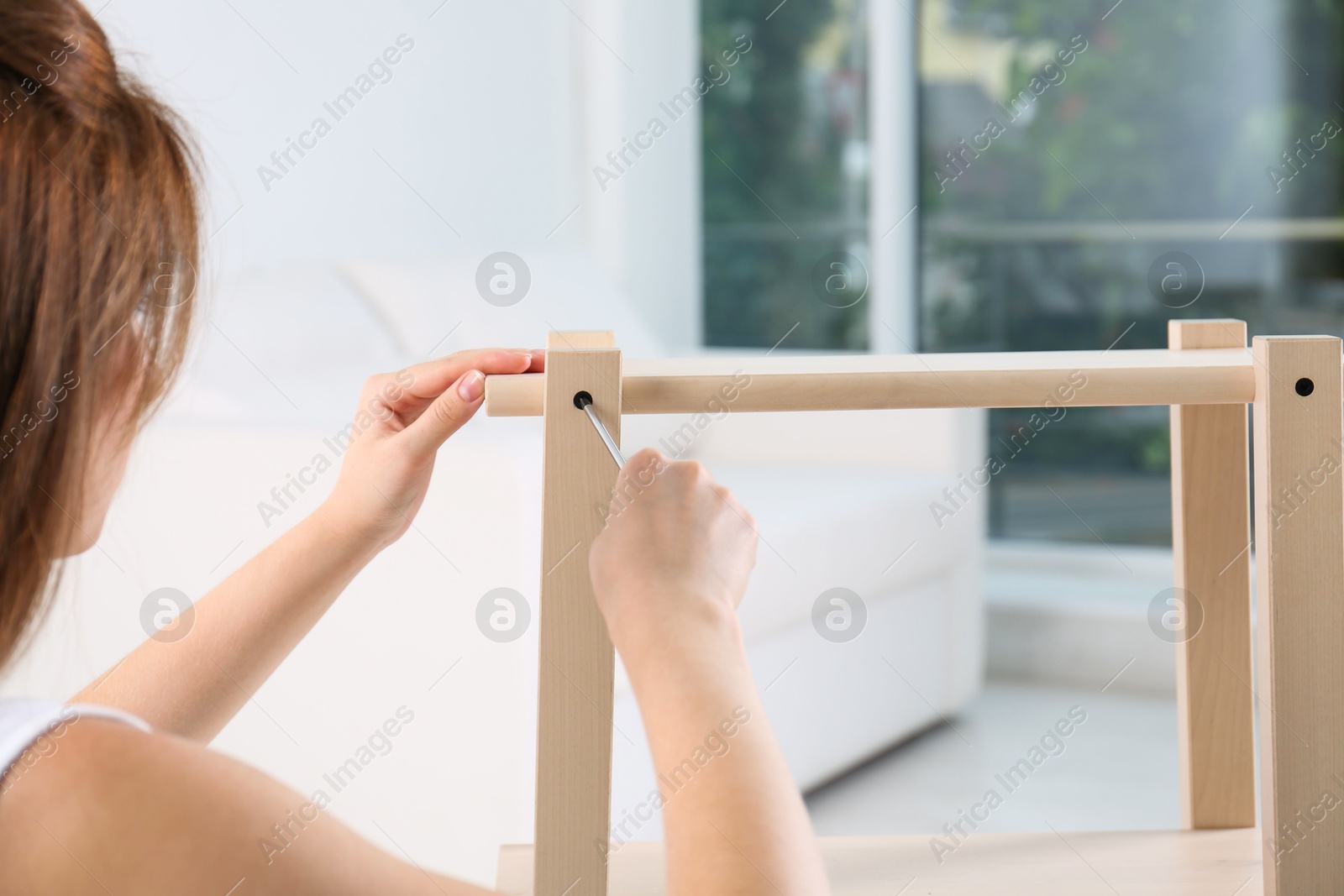 Photo of Woman with screwdriver assembling furniture at home