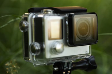 Photo of Modern action camera in grass outdoors, closeup