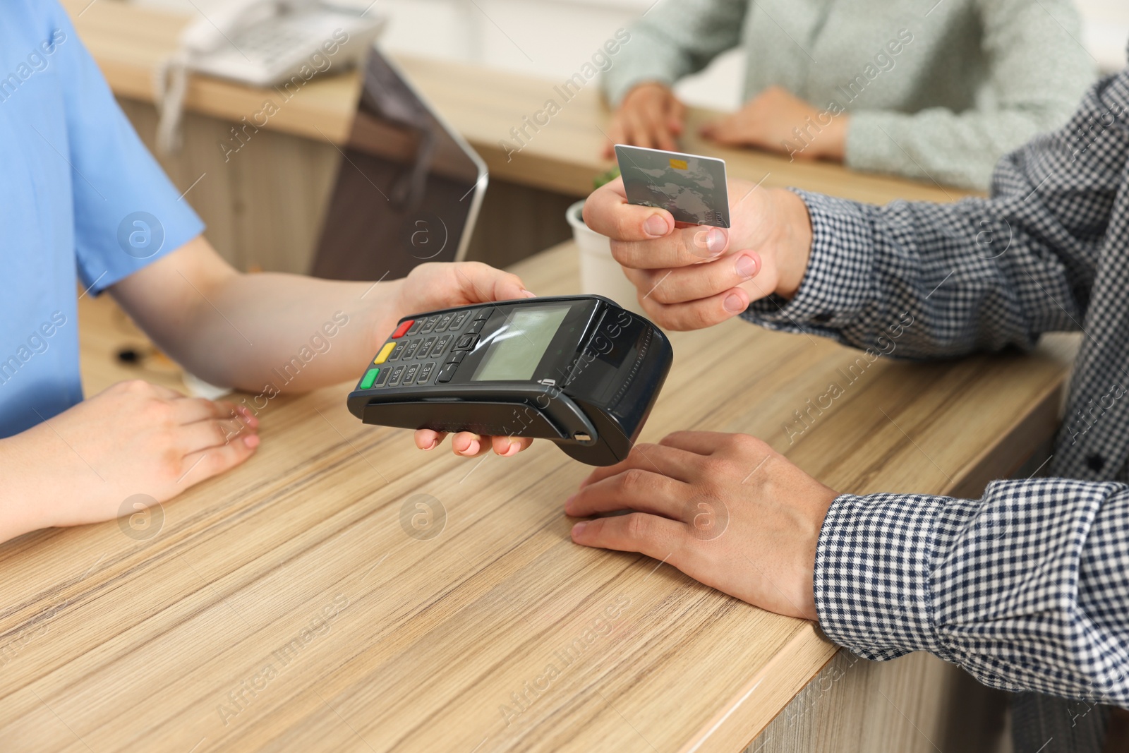 Photo of Receptionist taking payment from client via terminal at hospital, closeup