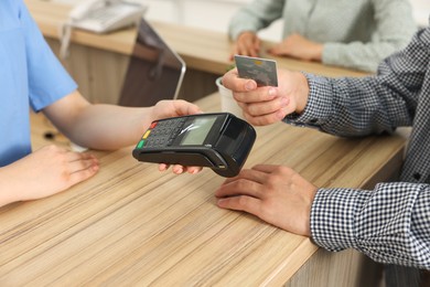 Receptionist taking payment from client via terminal at hospital, closeup