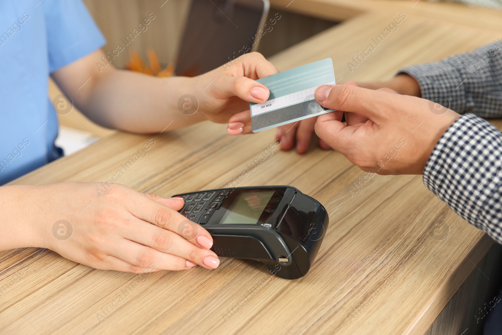 Photo of Receptionist taking payment from client via terminal at hospital, closeup