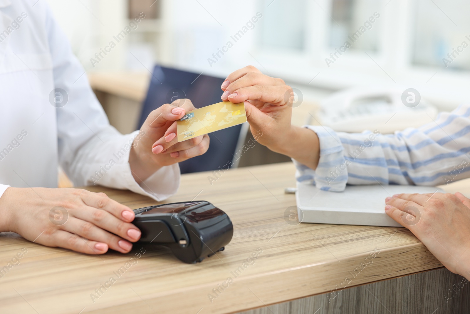 Photo of Receptionist taking credit card from client at hospital, closeup