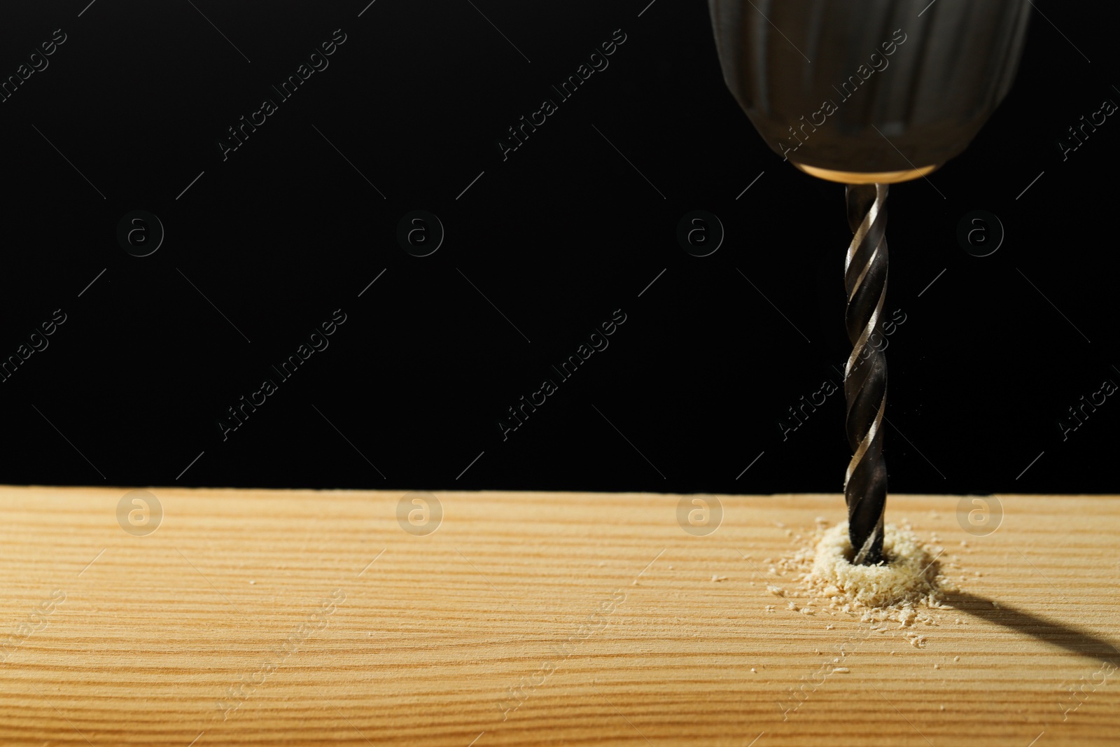 Photo of Drilling hole in wooden plank on black background, closeup. Space for text