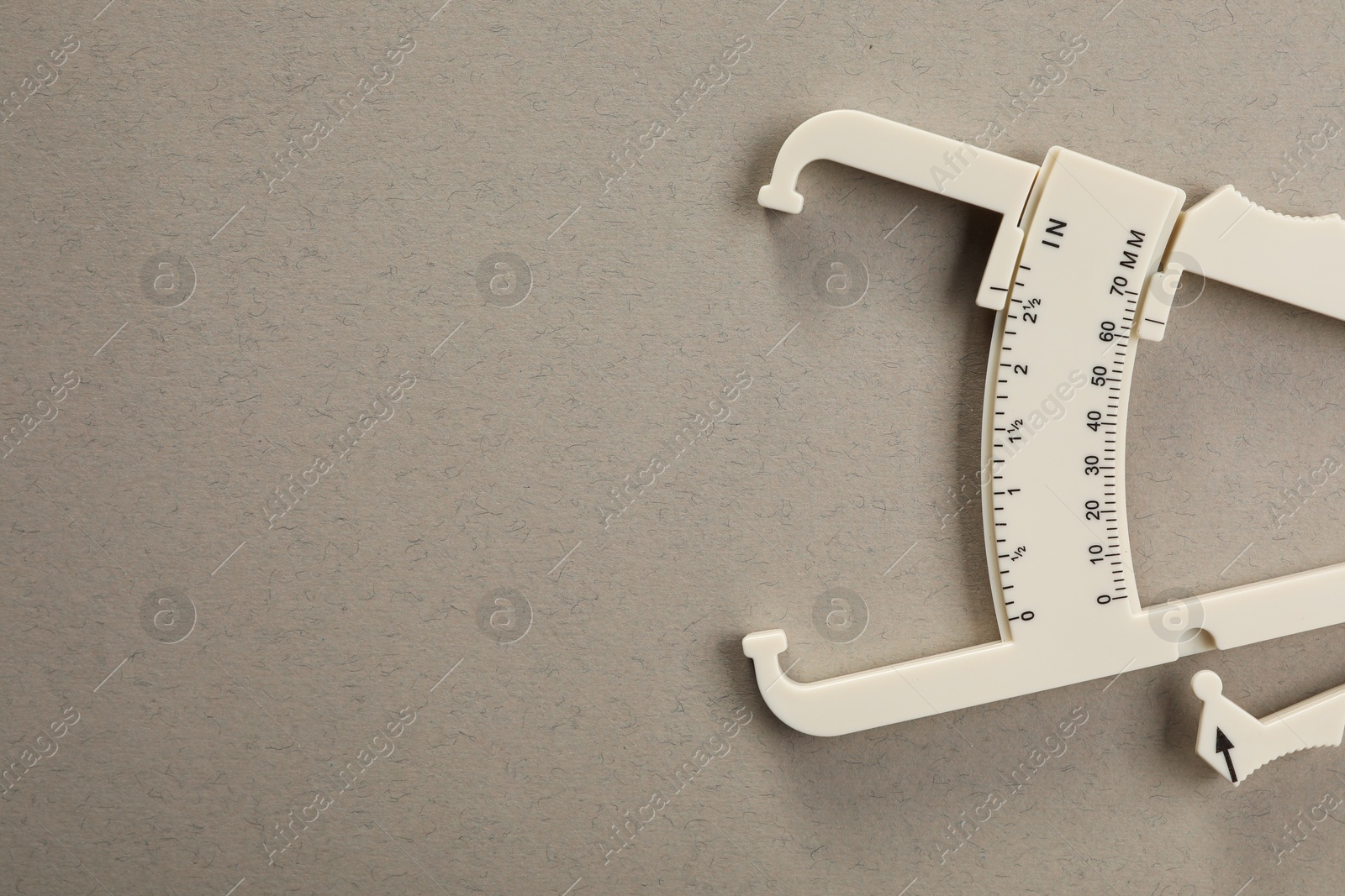 Photo of Plastic body fat caliper on grey background, top view. Space for text