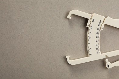 Plastic body fat caliper on grey background, top view. Space for text